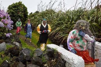 Three Okalolies escorting Louise Kendall down a path and through a gate (at the Residency?)