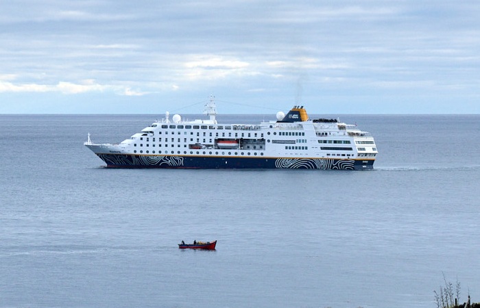 The MS Hamburg off the settlement with an island fishing boat in the foreground.