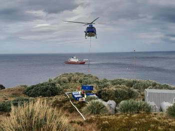 Helicopter lowering a container at the Gough Island base. Photo: Nathan Swain