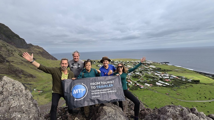 A group of intrepid Most Traveled People unfurl their banner atop the 1961 volcano. Photo: Phillips Connor