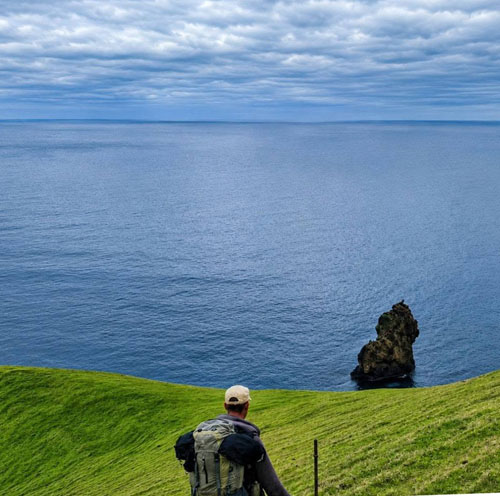 A hunter pauses to look out to see while on Hillpiece with the Hillpiece Hardies partly visible below.