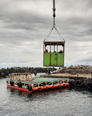 Passengers being lifted from the harbour onto the raft in the box.