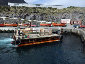 A raft of shipping crates is brought into the harbour