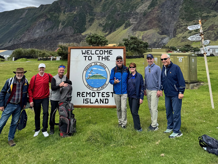 The golfers by the 'Welcome to the Remotest Island' sign
