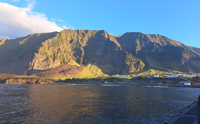 The sun-bathed view the R&Gs had of the settlement and cliffs from the ship