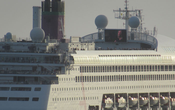 Close-up of passengers lining the rails of the Ambience off the settlement